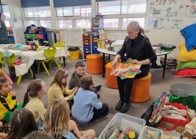 Children gathered around Kathleen who is holding a painting