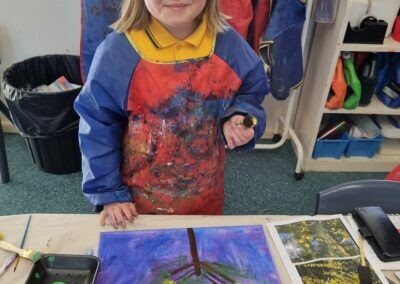 Student in front of table with painting of Wattle